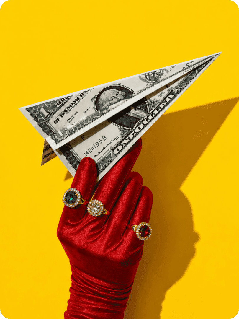 Paper airplane made from a dollar bill in a red glove